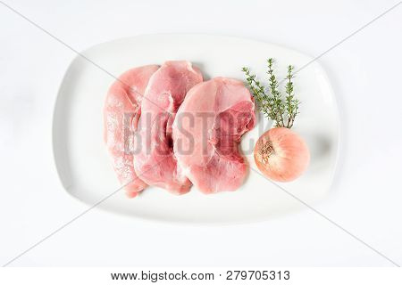 Food, Freshness Raw Pork Chop Put On White Plate Decorated With Green Leaves, Onion, Garlic And Thym