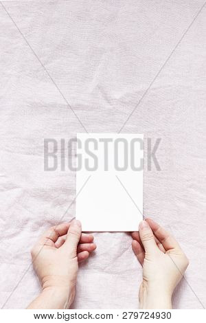 Closeup Of Womans Hands Holding Blank Paper Card. Greeting Card Mock-up. Pink Linen Background. Vale