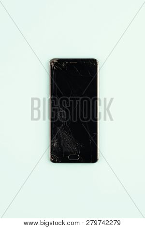 Mobile Phone With Broken Black Screen, Top View. Distressed Damaged Smartphone In Pale Green Backgro