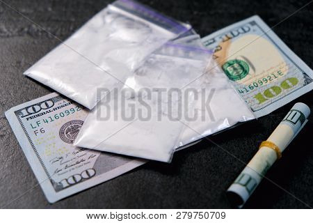 Rolled Hundred Dollars Banknote And Plastic Packet Of Cocaine On Black Background