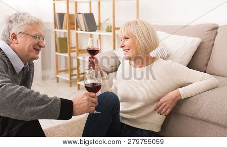 Senior Couple Enjoying Glass Of Wine, Having Rest At Home