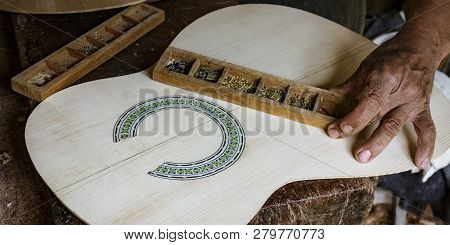 Man Puts Finishing Touches On The Inlay Around A Soundhole In A New Instrument