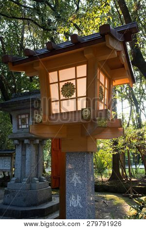 Miyazaki, Japan - November 5, 2018: Modern stone lantern decorated with a golden chrysanthemum at the Miyazaki Jingu shrine grounds at dusk