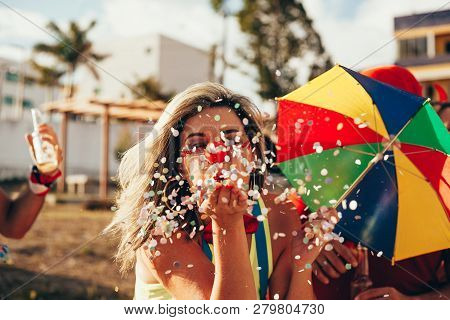 Brazilian Carnival. Young Woman In Costume Enjoying The Carnival Party Blowing Confetti
