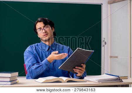 Young male teacher in front of chalkboard  