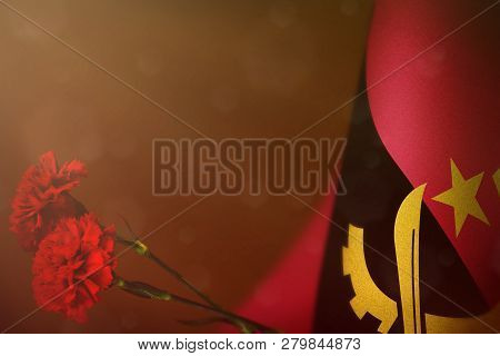 Angola Flag With Two Red Carnation Flowers For Honour Of Veterans Or Memorial Day On Orange Dark Vel