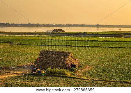 Mandalay, Myanmar - January 20, 2016: Burmese Woman Draws Water From A Well At Sunset With Taun Tha 