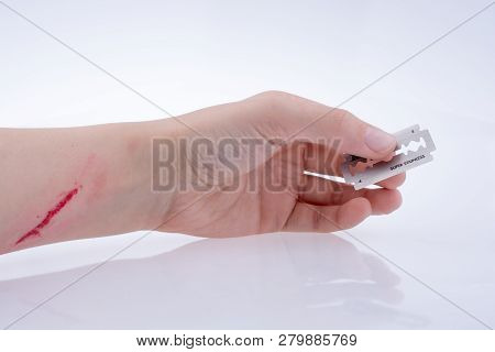 Injured Hand Holding A Razor Blade On A White Background