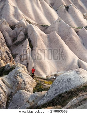Amazing day in Cappadocia mountains, Turkey. Photographer in red jacket taking photo of amazing hills. Landscape photography