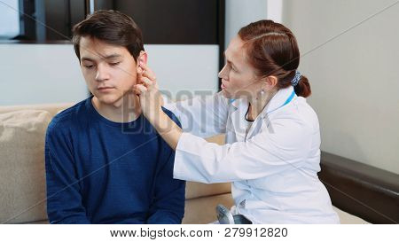 Woman Doctor Puts A Hearing Aid On A Young Guy.