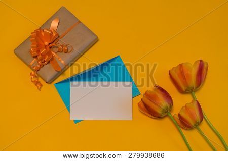 Orange Tulips, Gift Box, Empty Card And Evenlope On Bright Yellow Background. Beautiful Spring Mock 