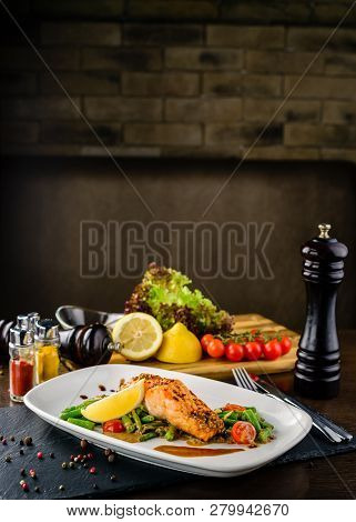 One Piece Of Baked Grillen Salmon Filet Pepper Lemon And Salt, With Vegetables Served On Black Stone