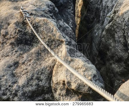 Stainless Twisted Rope Anchored In Rocky Wall. Stair Climbing And Iron Rope On Mountain Via Ferrata