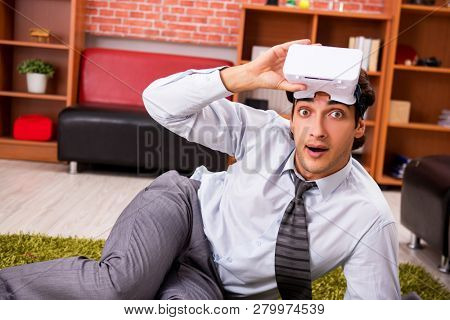 Young employee with virtual glasses during break in the office 