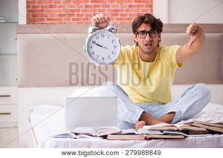 Young student studying in bed for exams