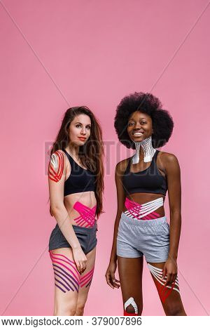 Kinesiology Taping. Two Young Female Athletes On Pink Background With Kinesiology Tape On Neck, Shou