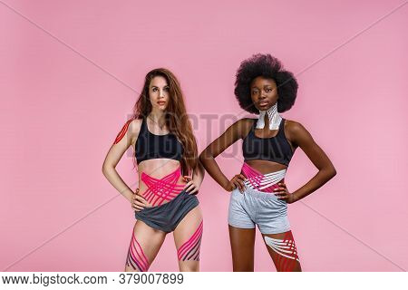 Kinesiology Taping. Two Young Female Athletes On Pink Background With Kinesiology Tape On Neck, Shou