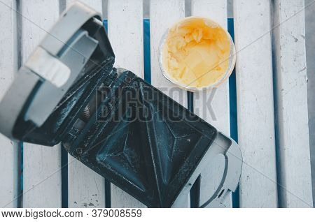 Sandwich Maker Opened And Butter On Wood Table. Angled View With The Hinged Lid Partially Open To Re