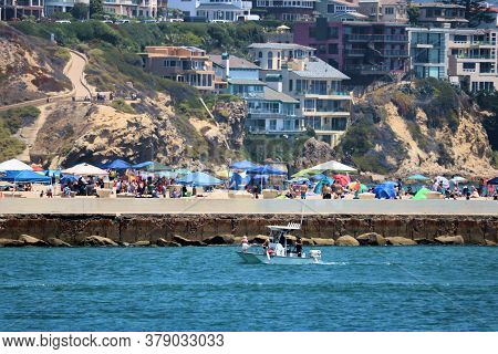 July 30, 2020 In Newport Beach, Ca:  Boat Riding Into The Harbor With Beachgoers Sunbathing On The S