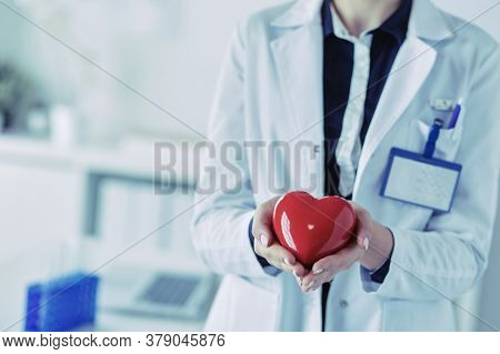 A doctor with stethoscope examining red heart, isolated on white background