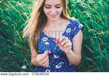 European Girl Holds A Daisy Flower And Tears Off The Petals