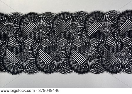 Black Gray Color Straight Strip Of Lace Fabric On Gray Background. Elastic Silk Nylon Braid Border. 