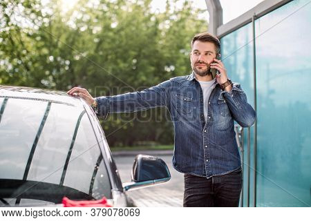 Car Celaning And Polishing Outdoors. Portrait Of Young Caucasian Man Standing Near His Car At Self S