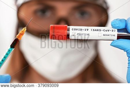 Hand In Blue Gloves Holding Vial With Blood, Label Says Covid-19 Test, Positive Result Checked, Blur