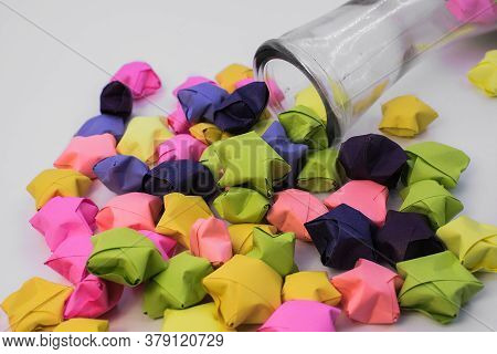 Craft Made Of Colored Paper In The Form Of Stars. Colorful Stars Fall Out Of A Glass Bottle