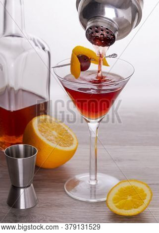 Pouring A Negroni Cocktail In A Martini Glass, Gin Cocktail, Orange And Cherry Garnish