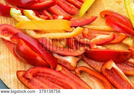 Slicing Red And Yellow Sweet Peppers On Wooden Cutting Board