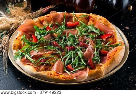 Pizza With Prosciutto Parma Ham, Arugula Salad Rocket And Strawberries On Wooden Background Italian 
