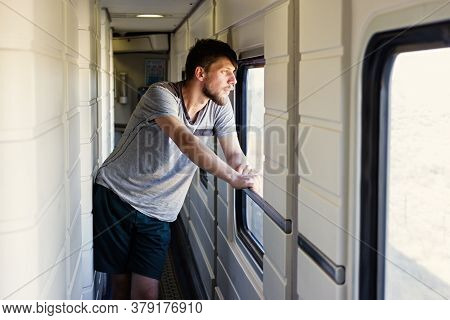 Middle Plane Portrait Of A Handsome Young Caucasian Man With A Beard, Looks Outside Of The Trains Wi