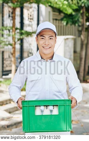 Portrait Of Happy Handsome Vietnamese Milkman Carrying Green Plastic Milk Crate