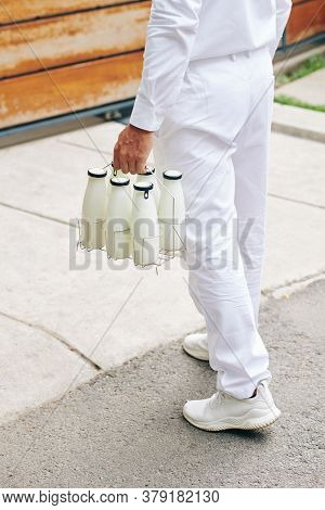 Delvery Man Carrying Glass Bottles To Entrance Of Customer