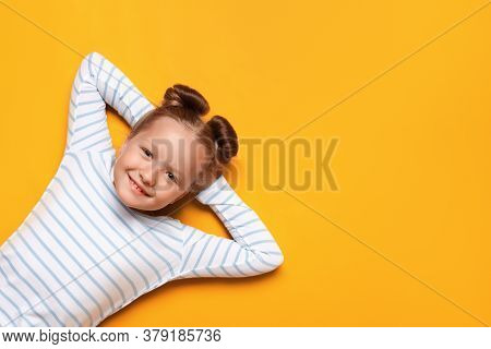 Portrait Of A Cute Attractive Adorable Little Girl With Hair Buns On A Yellow Background. The Child 