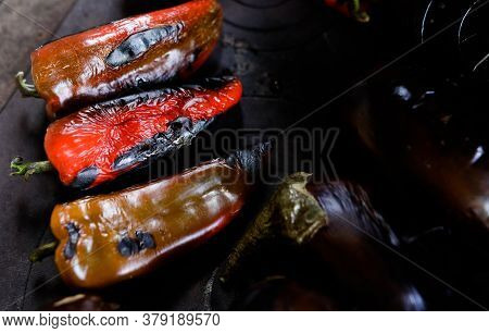 Details With Roasted Red Paprikas And Eggplants On Top Of An Outdoors Metal Stove With Wood Fire.