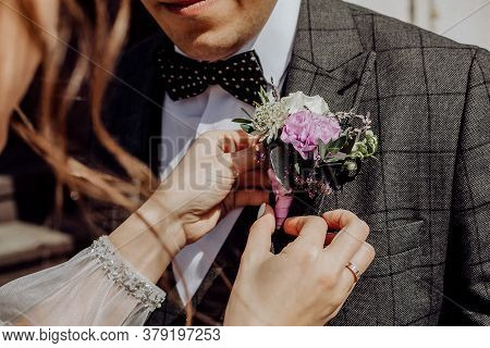 Stylish Buttonhole On The Jacket Of The Groom, The Bride Helps To Attach The Buttonhole To The Jacke