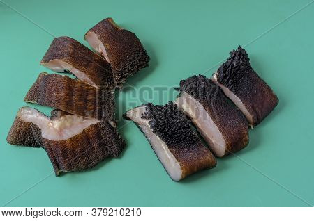 Pieces Of Raw Cow Stomach On Turquoise. Random Pieces Black Unpeeled Tripe With Grass Residues. Beef