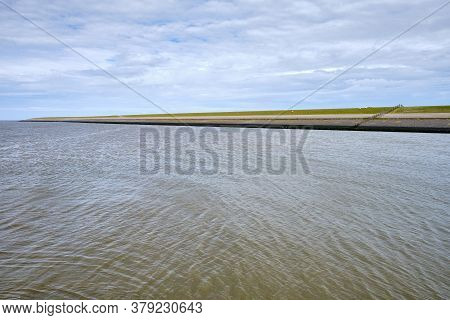 Typical Dutch View Of A Dike, Seawall, With Sheeps Green Grassland And The Wadden Sea. Sedyk, Friesl