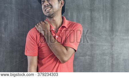 Young Asian Man Suffering From Neck Pain On Cement Wall Background With Copy Space, Problems And Hea