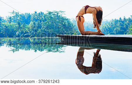 Stretching On Sunrise Background. Active Woman In Bikini Practicing Yoga At Villa Poolside To Keep F
