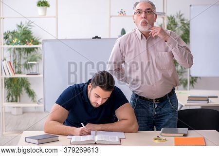 Old teacher and young male student in the classroom