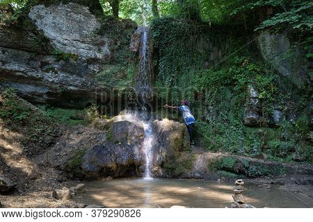 Black Woman Reach Out To The Water Of A Waterfall At A Hot Day In Summer. Linner Waterfall Is The Bi