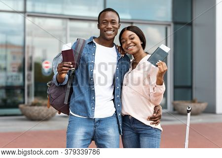Ready For Vacasion. Excited Black Spouses Posing Near Airport With Passports In Hands, Smiling At Ca