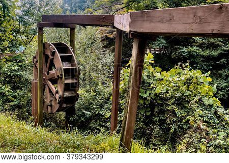 Wooden Water Trough And Waterwheel In Lush Mountain Recreational Park