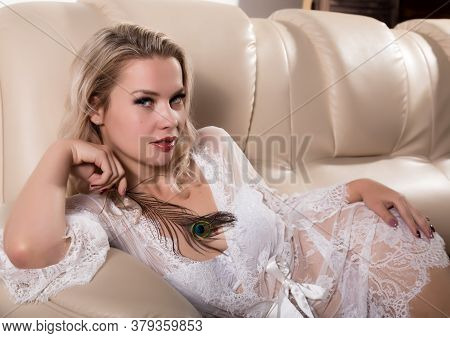 Gentle And Seductive Blonde Woman With Attractive Body In White Lacy Lingerie Lying On Sofa. Sensual