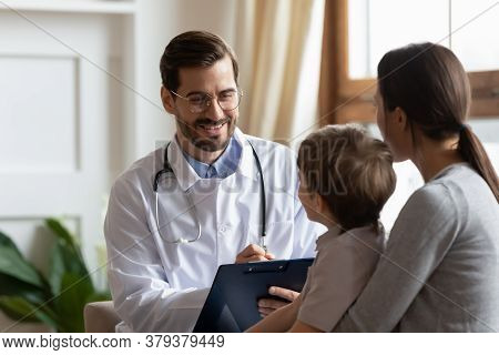 Smiling Male Pediatrician Listening To Young Mother With Kid Son.