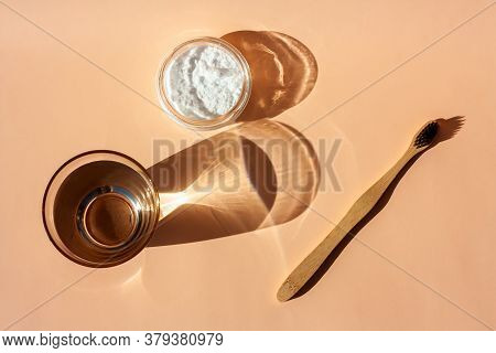 Bamboo Toothbrush, Glass Of Water And Toothpaste Powder On A Peach-colored Pastel Background. Biodeg