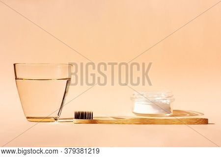 Bamboo Toothbrush, Glass Of Water And Toothpaste Powder On A Peach-colored Pastel Background. Biodeg